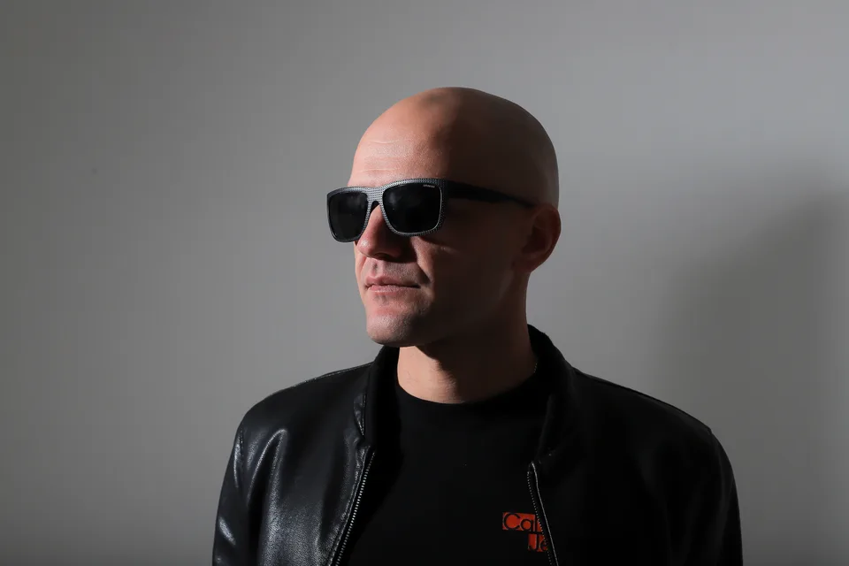 GANGSTANTIN wearing sunglasses against a gray studio background.