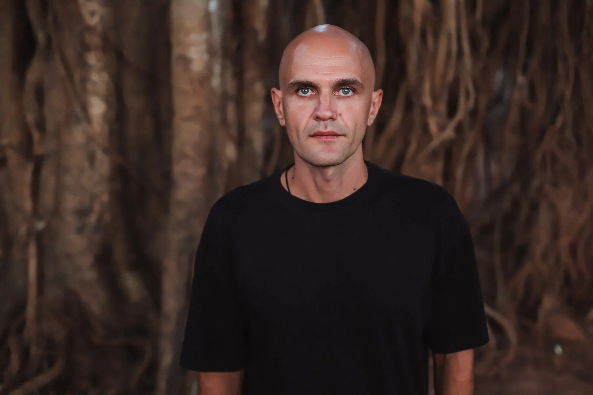GANGSTANTIN portrait in front of large tree roots.