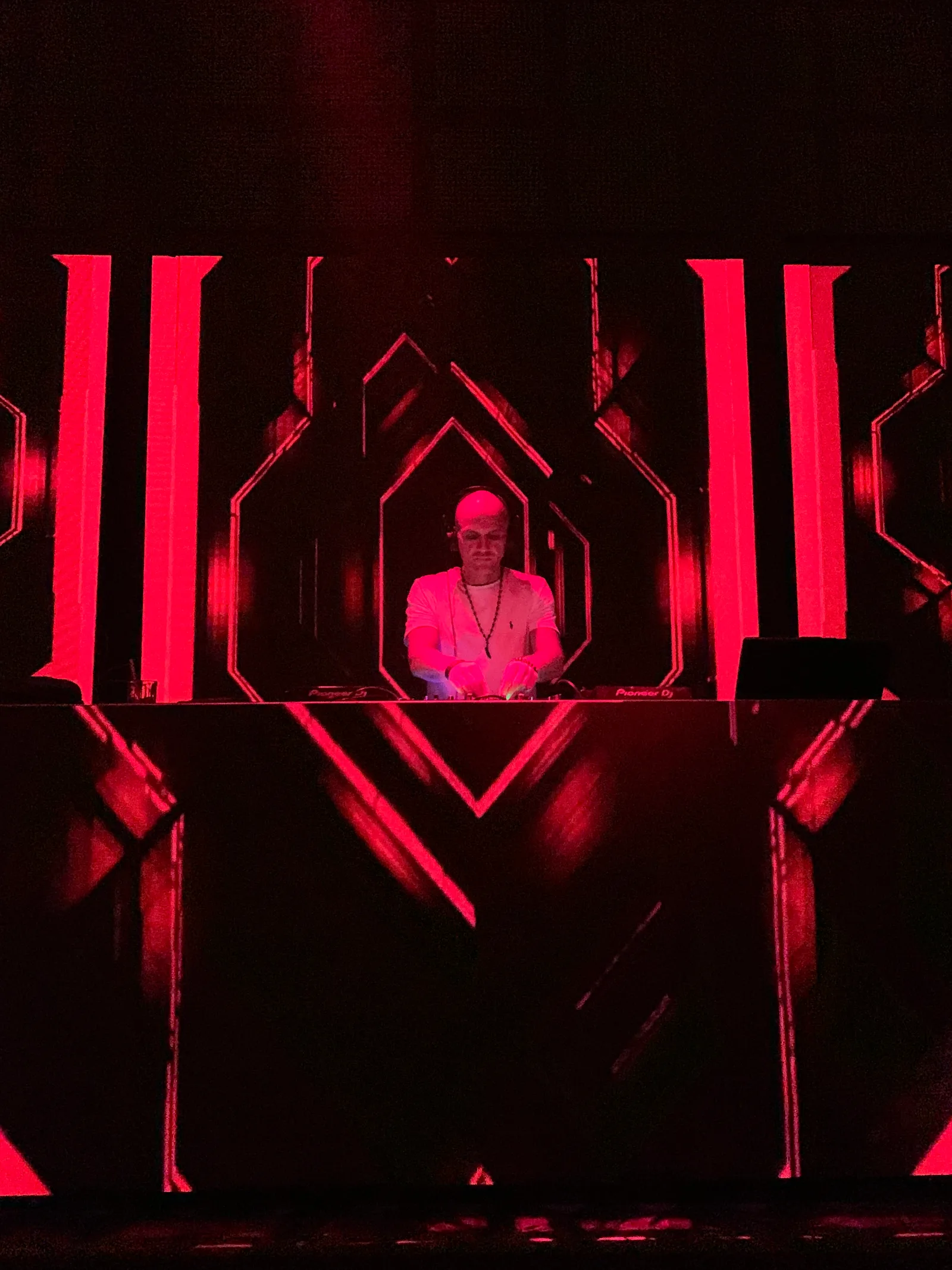 GANGSTANTIN performing at a DJ booth under red geometric visuals.