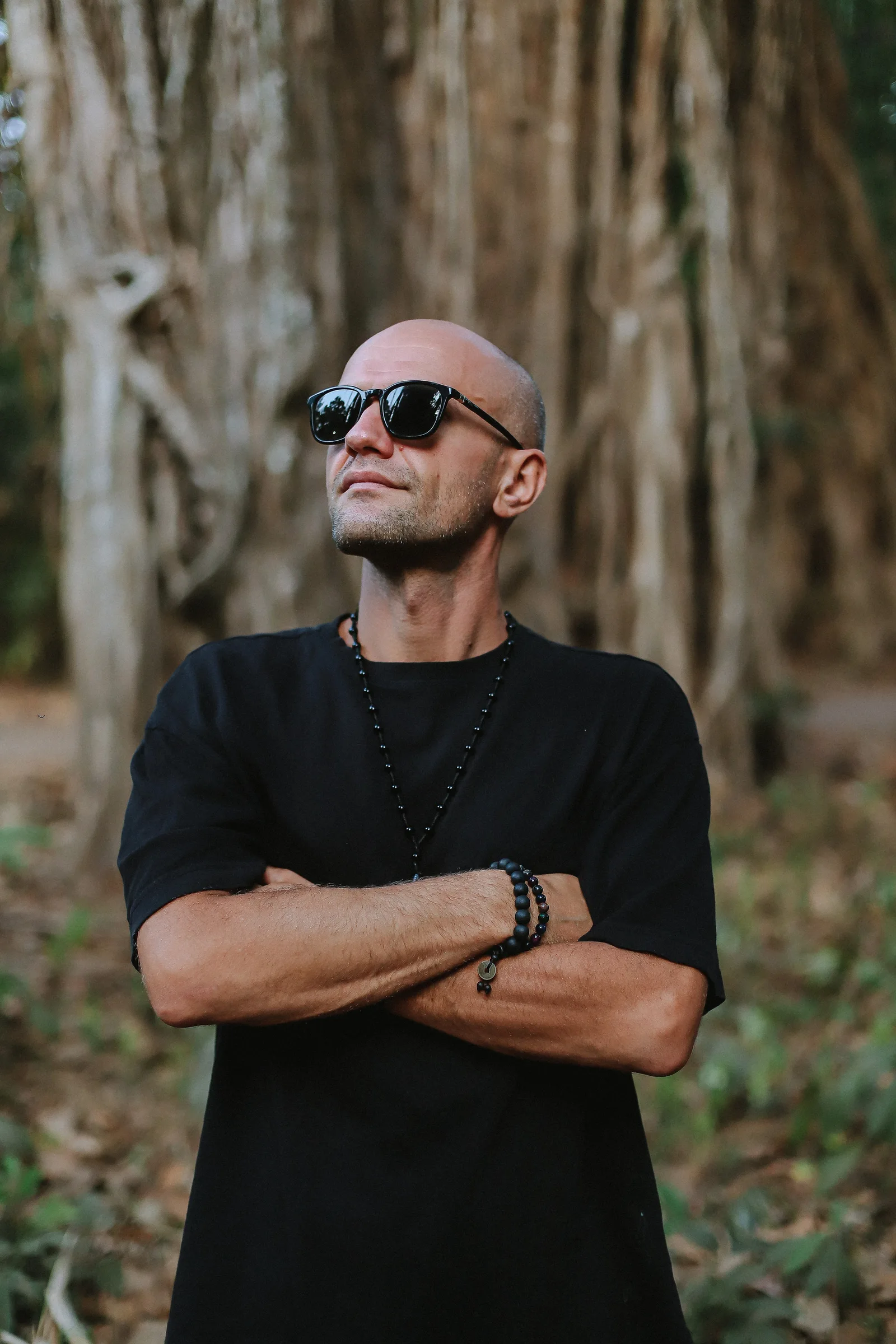 GANGSTANTIN wearing sunglasses in front of large tree roots.