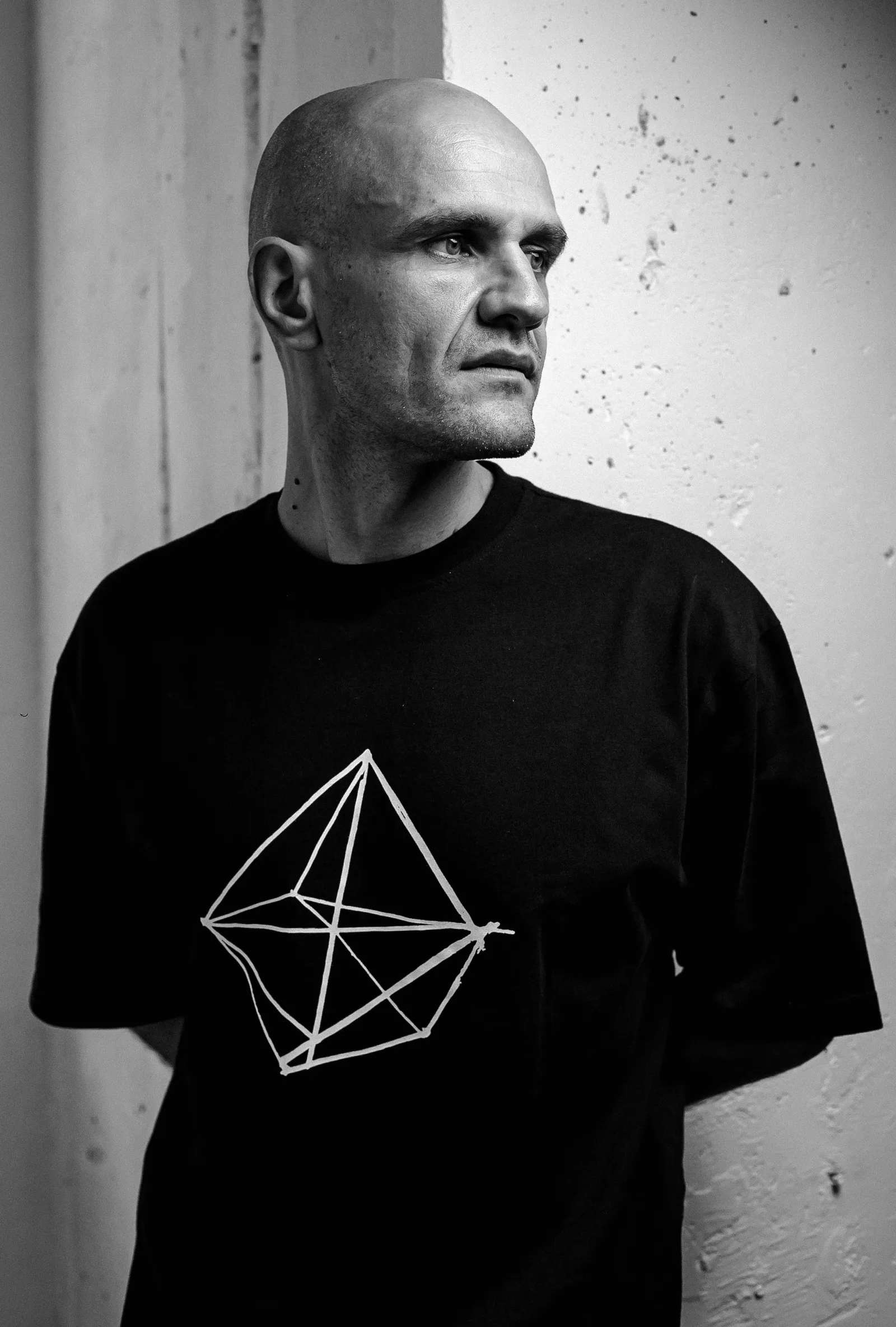 Monochrome portrait of GANGSTANTIN against a textured wall.