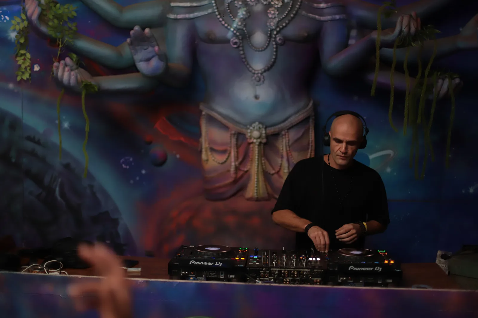 GANGSTANTIN performing at a DJ booth beside a painted mural.