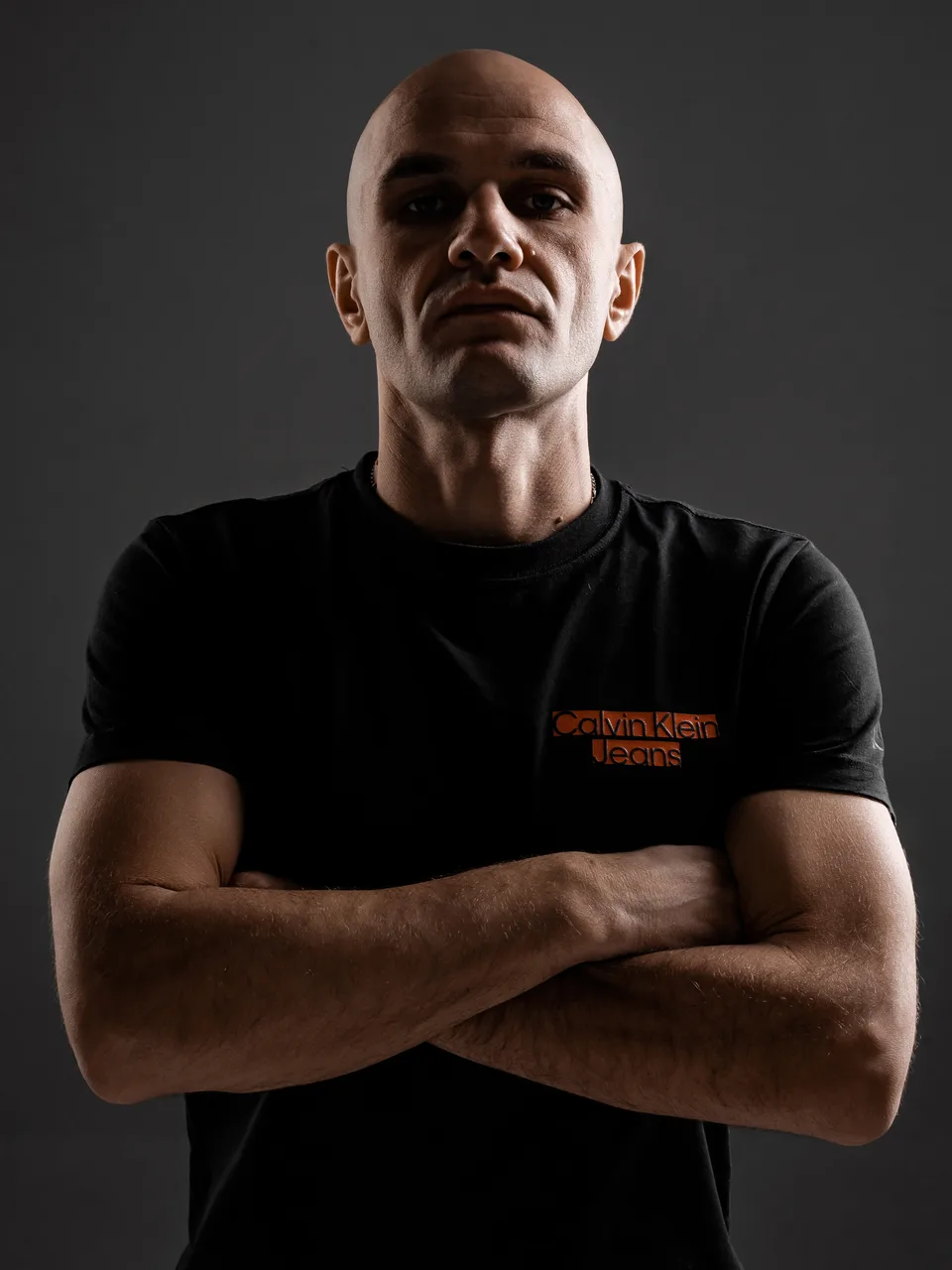 Low-angle studio portrait of GANGSTANTIN with folded arms.