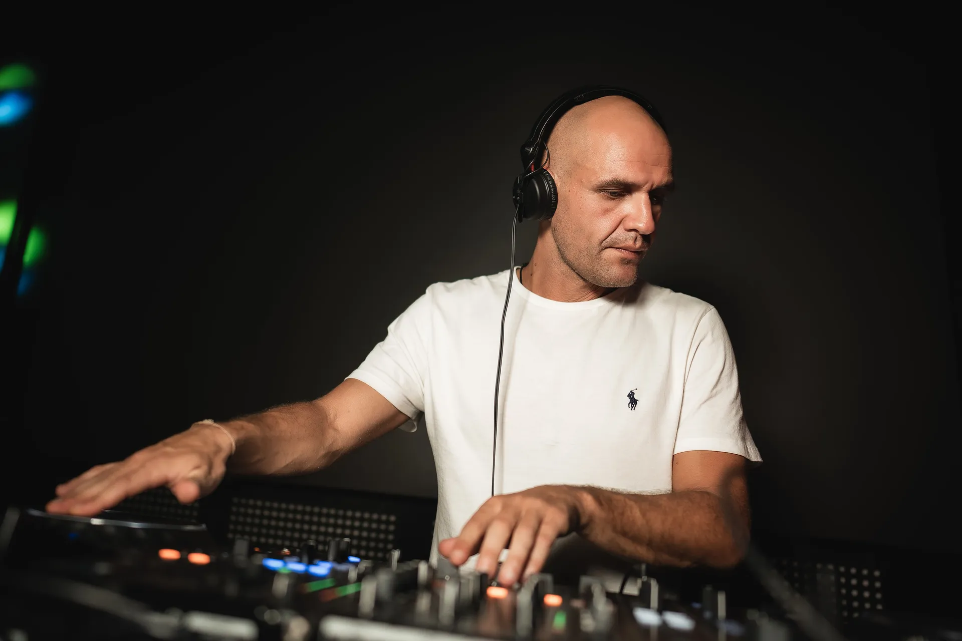 GANGSTANTIN performing at a DJ booth against a dark background.