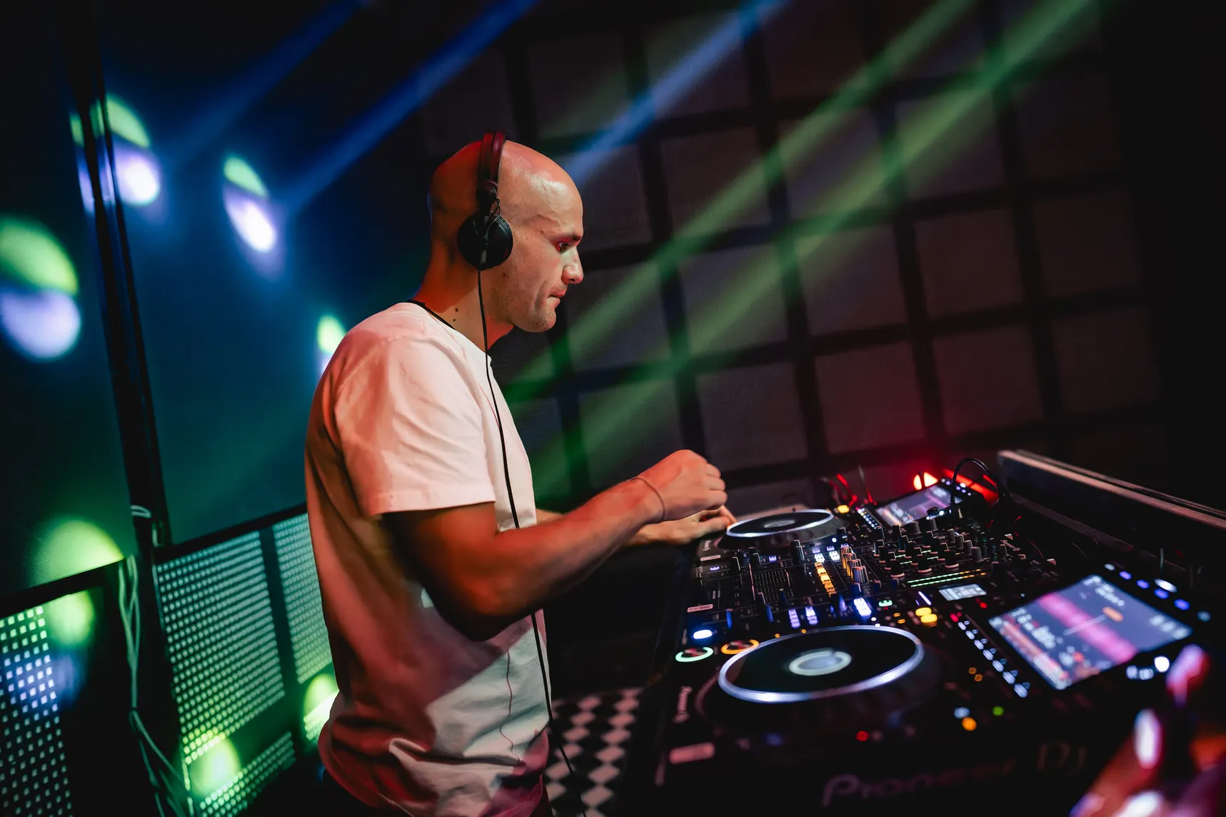 GANGSTANTIN performing at a DJ booth under green and blue lights.