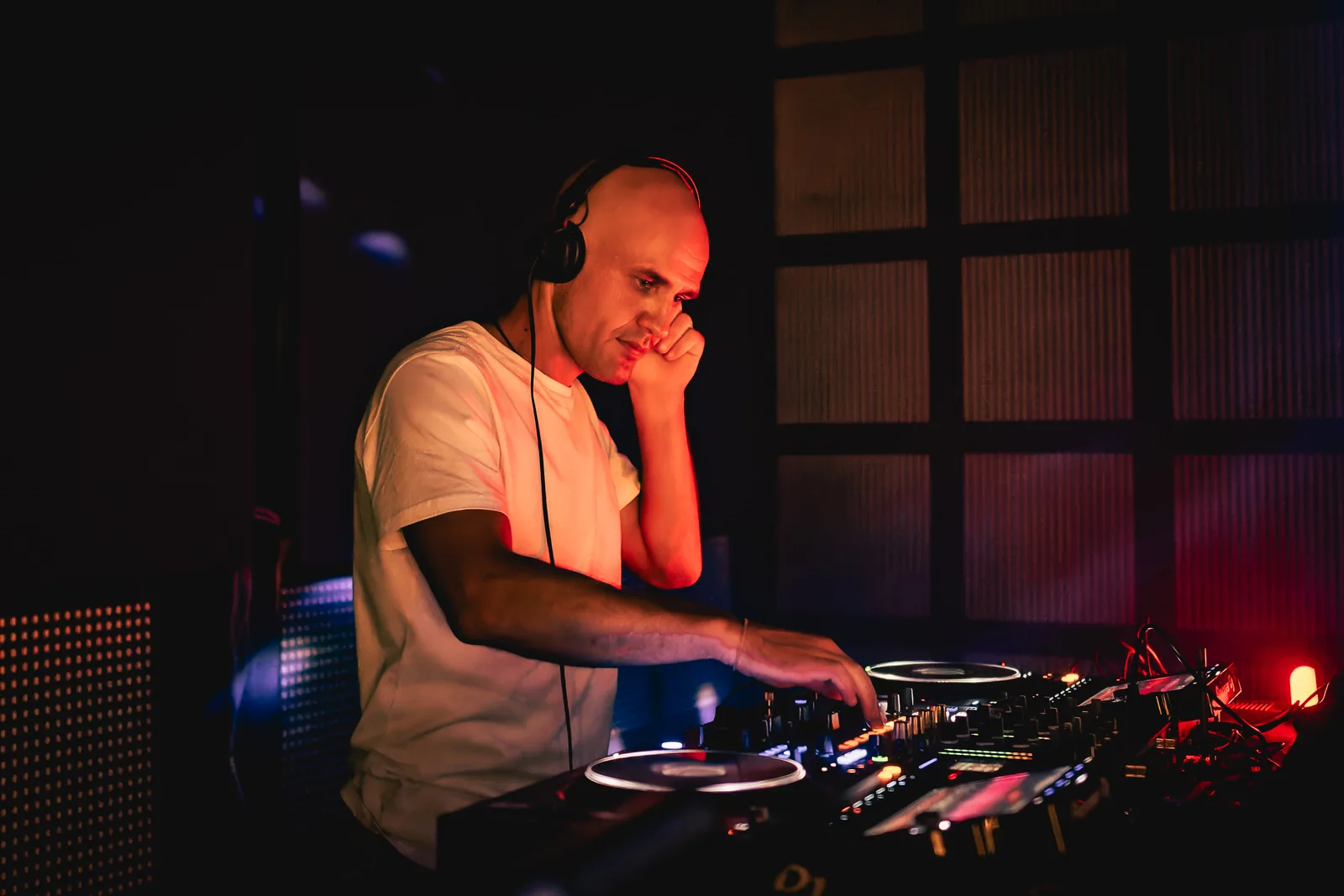 GANGSTANTIN performing at a DJ booth under red stage lighting.