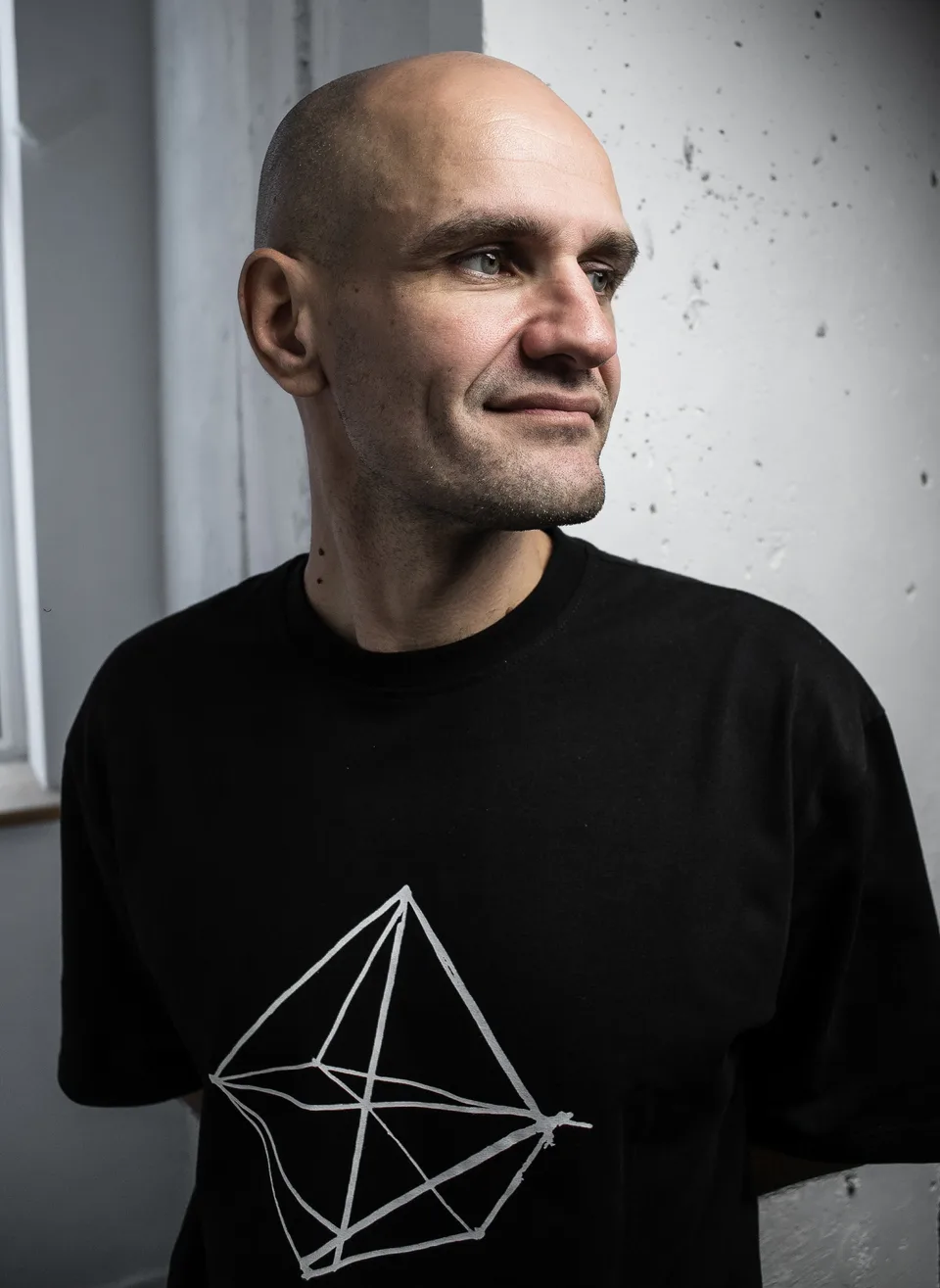 GANGSTANTIN portrait against a textured light wall.