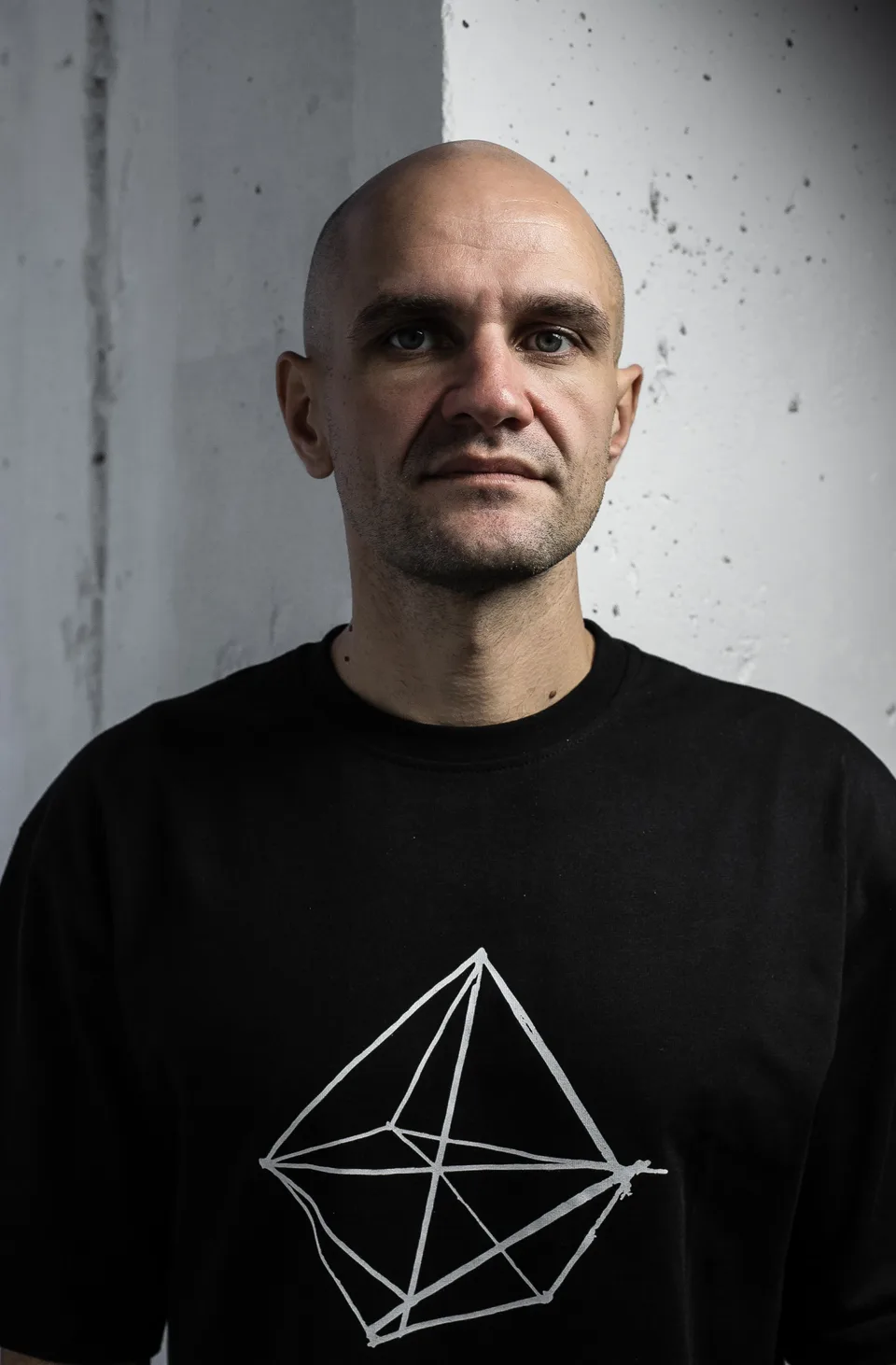 Front-facing portrait of GANGSTANTIN against a textured light wall.